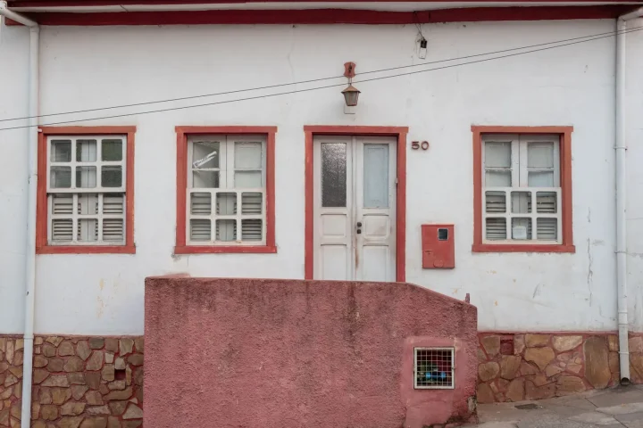 Casa antiga de paredes brancas e janelas coloridas