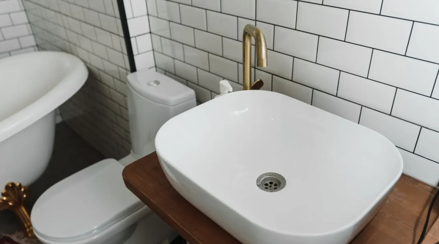 Banheiro com vaso sanitário e pia sobre bancada de madeira