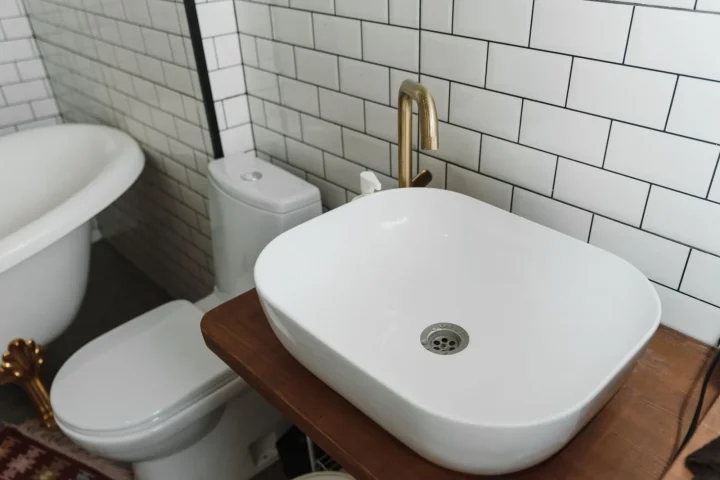 Banheiro com vaso sanitário e pia sobre bancada de madeira