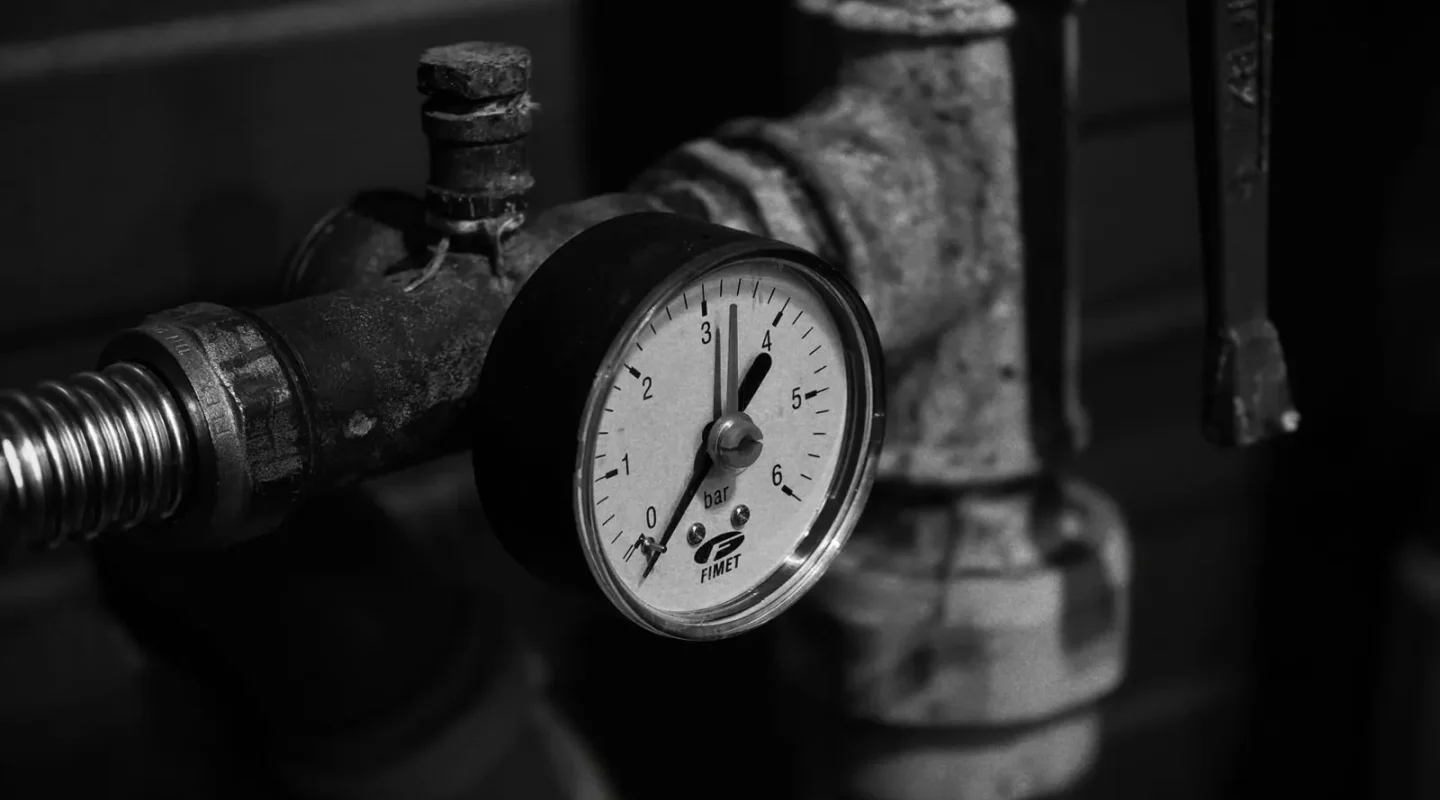 Manômetro antigo em uma tubulação industrial em preto e branco