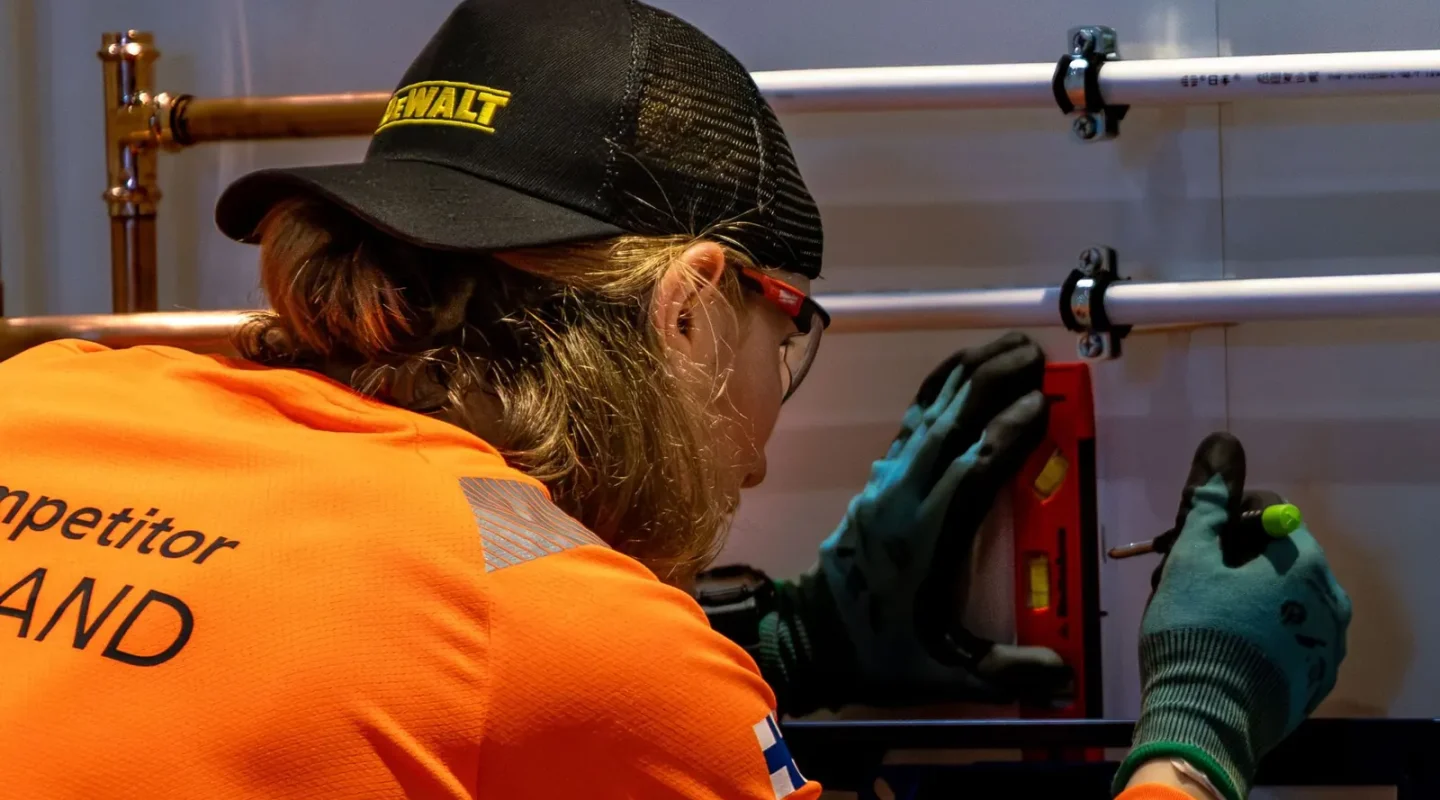 Profissional de camisa laranja alinhando tubos com ferramentas