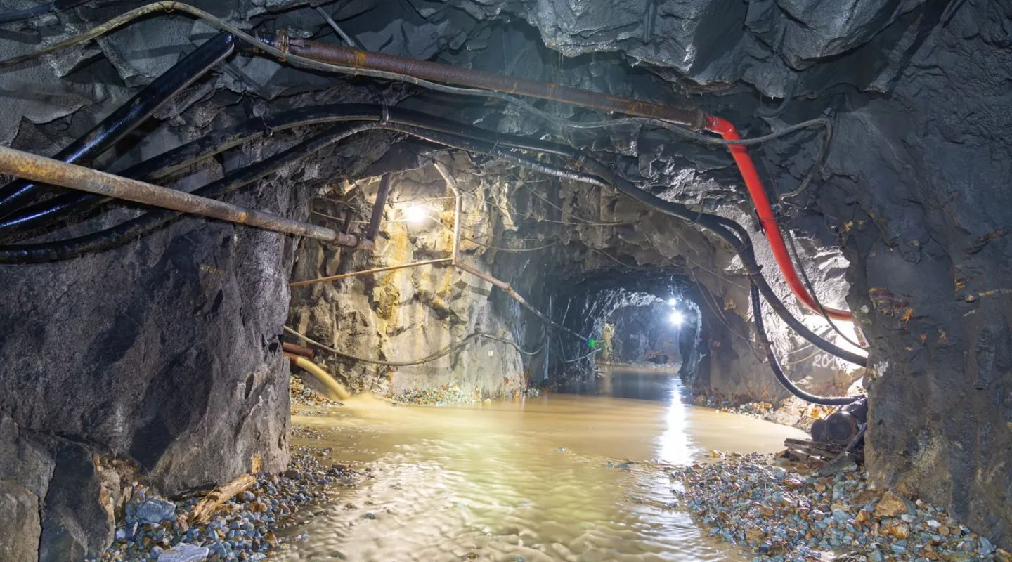 Túnel subterrâneo com água corrente e tubulações aparentes